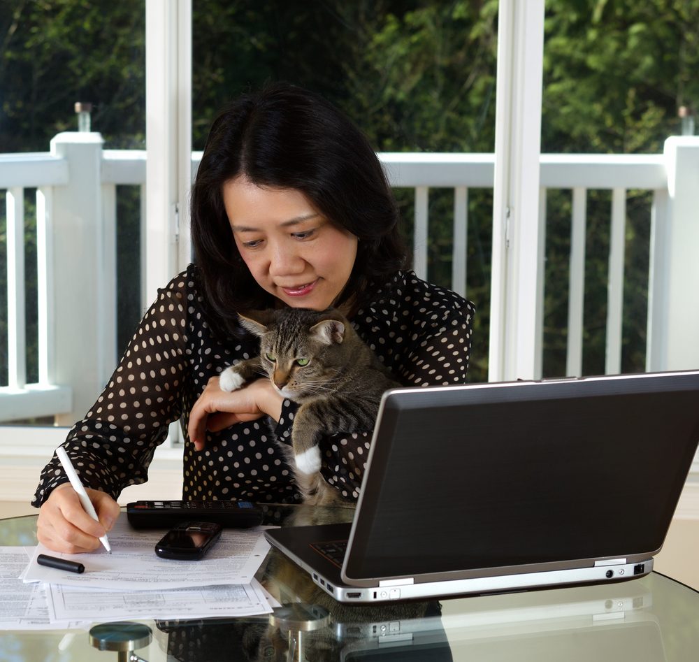 Woman taking notes with her cat by her side as she consults with Lauren over the Internet.